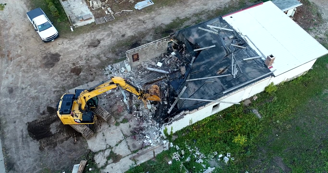 Ripresa aerea con drone di un escavatore che demolisce un vecchio edificio in cemento