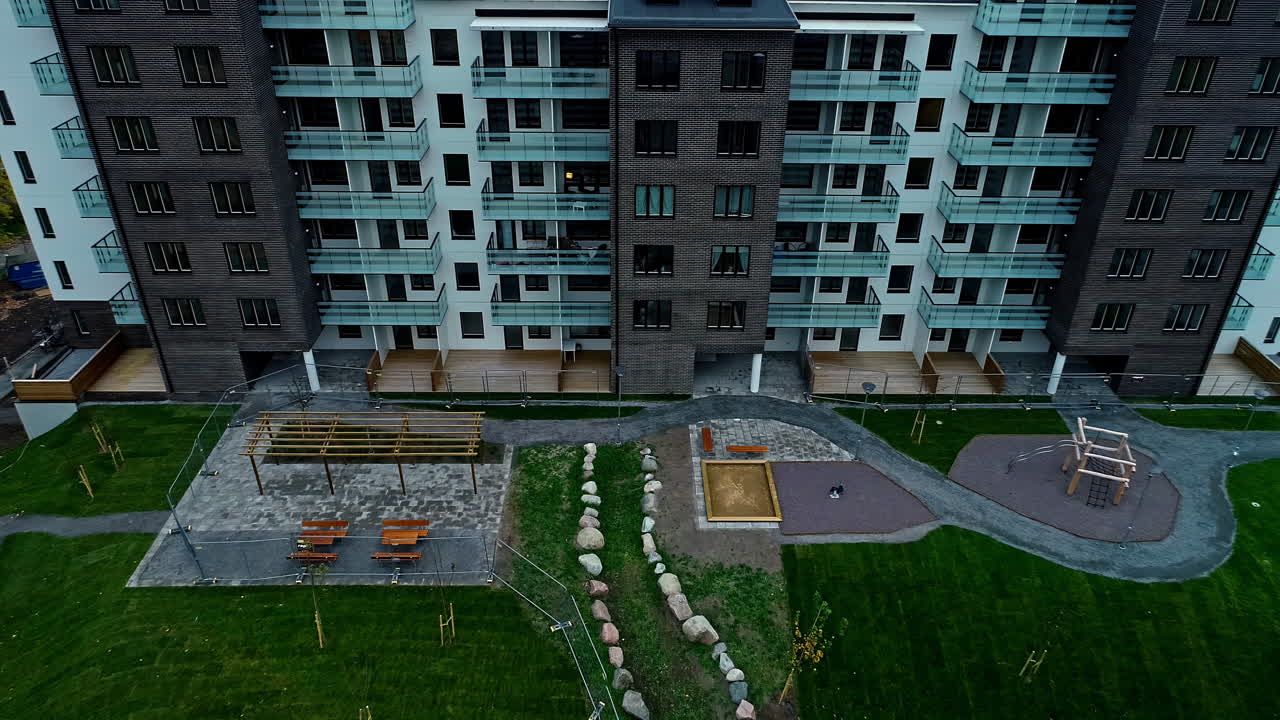 Exterior View Of High-rise Apartment With Playground And Green Lawn Outside The Building