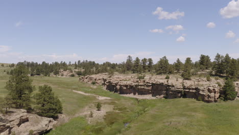 aerial views of a grassy plane heading to a beautiful rock formation in palmer lake colorado