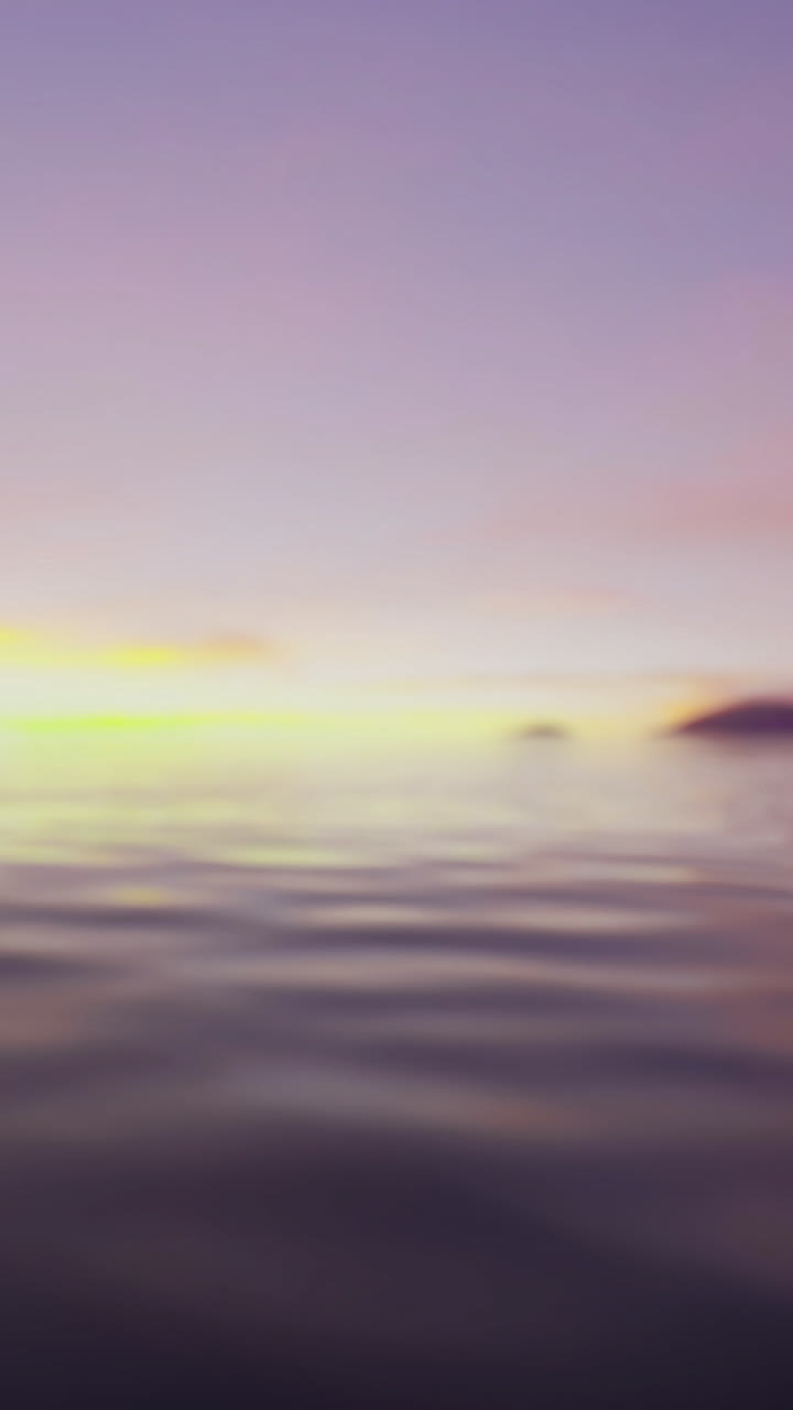 Sunset over the water with distant landforms in soft colors