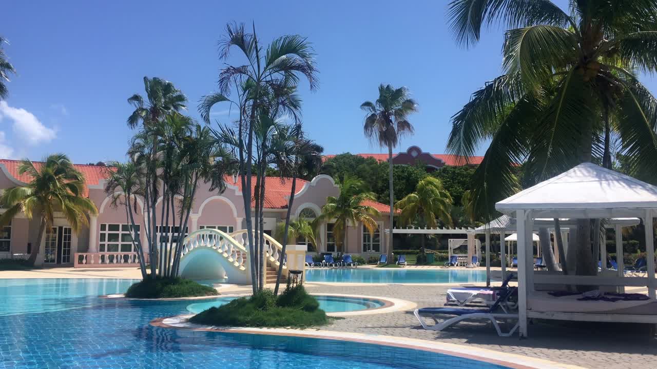 Swimming pool and palms in Caribbean resort, Varadero, Cuba in summer, panning shot