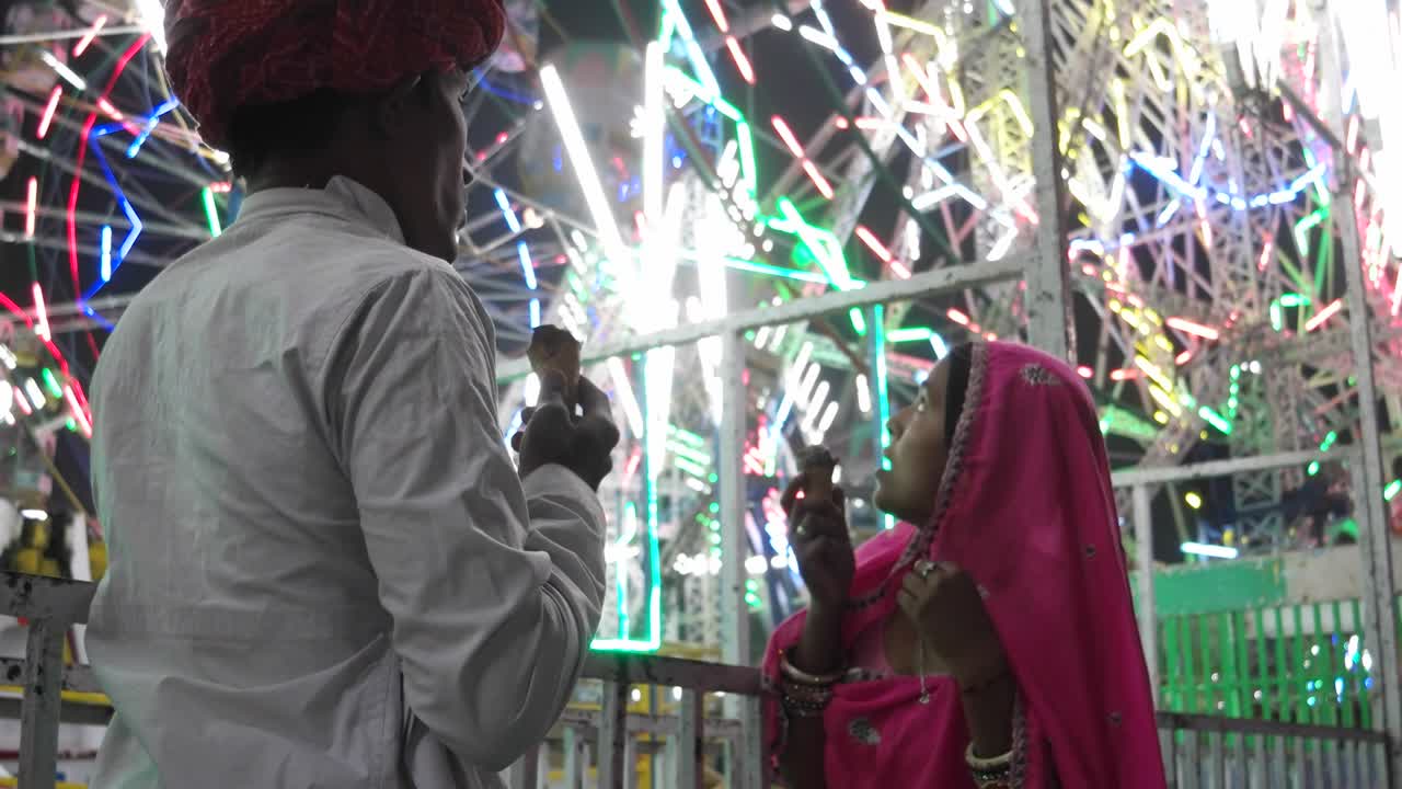 Indian couple eating ice cream in traditional dresses at the Pushkar Mela, a carnival of Rajasthan, India