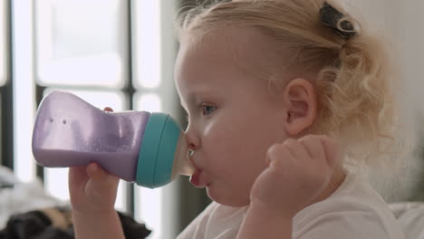 toddler girl drinking milk from the bottle