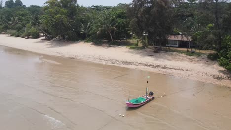 Vista-Aérea-Volando-A-Lo-Largo-De-La-Playa-Vacía-De-Ao-Kao-En-Koh-Mak-Pasando-Por-Un-Solitario-Barco-Pesquero-Amarrado-En-La-Arena