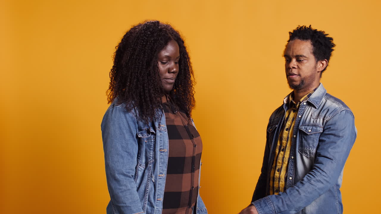 una alegre y positiva pareja casada jugando a las tijeras de papel de roca en el estudio