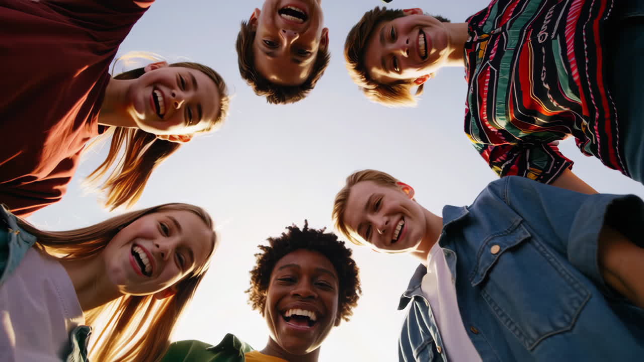 Happy group of diverse young friends looking down and smiling