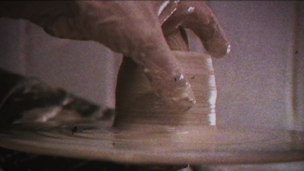 A potter teaches a woman to make clay dishes. A man takes a woman's hands. Vintage effect.