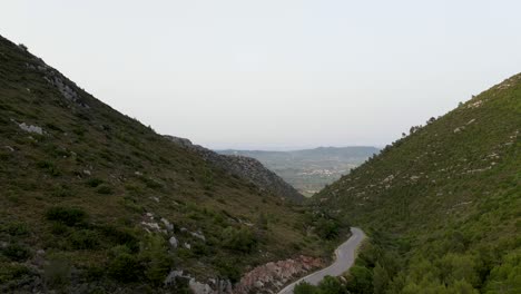 Ascendant-aerial-drone-view-of-winding-mountain-road-passing-and-valley-in-the-Ionian-island-of-Zakynthos,-Greece