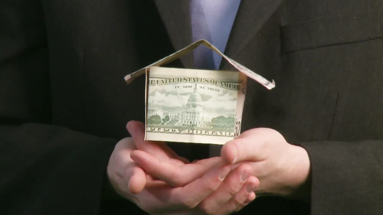 Businessman holding house of Dollars
