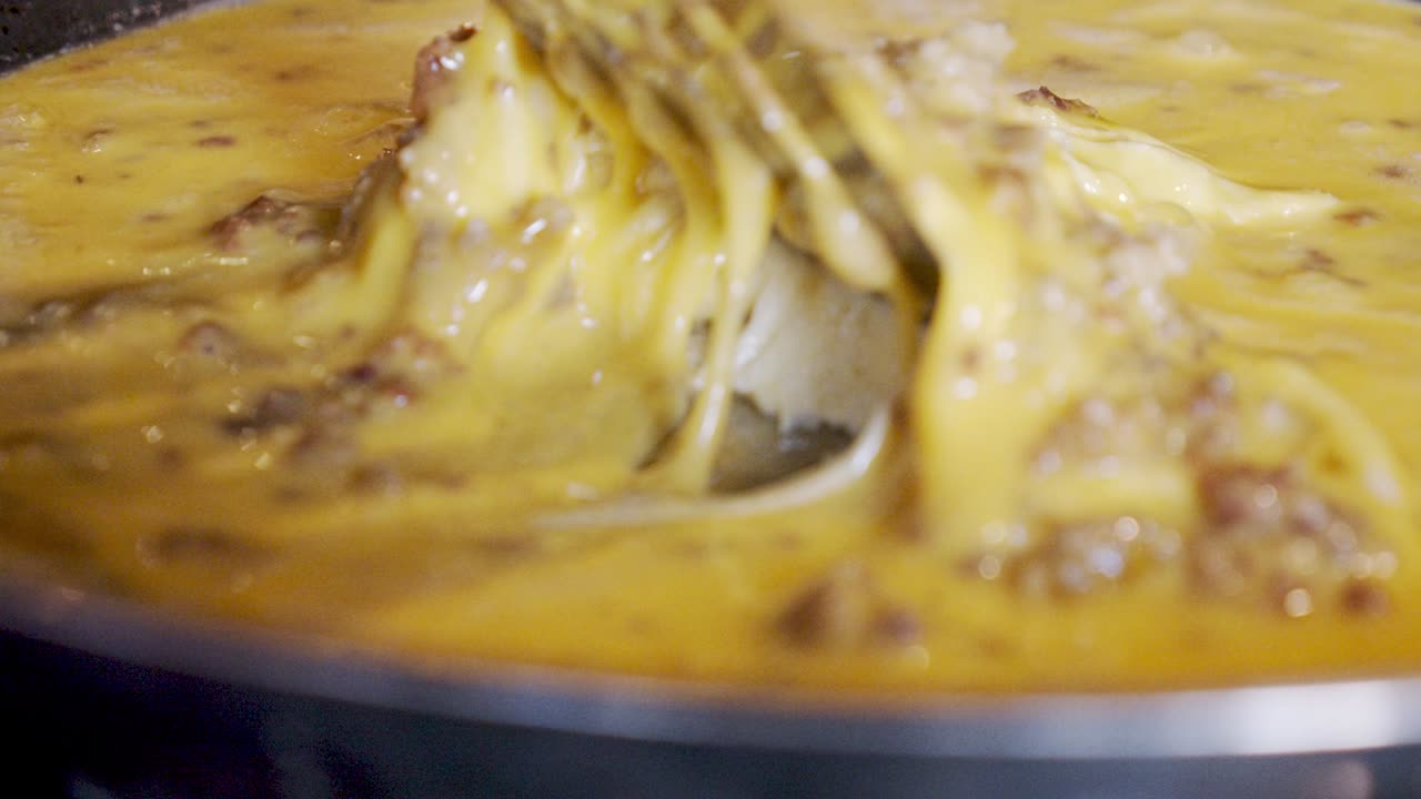 cierre los huevos para cocinar con trozos de salchicha en una sartén inoxidable en la estufa a cámara lenta