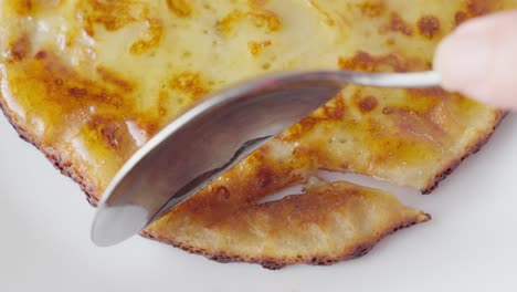 primer plano de una cuchara cortando un tentador panqueque recién cocinado con mermelada