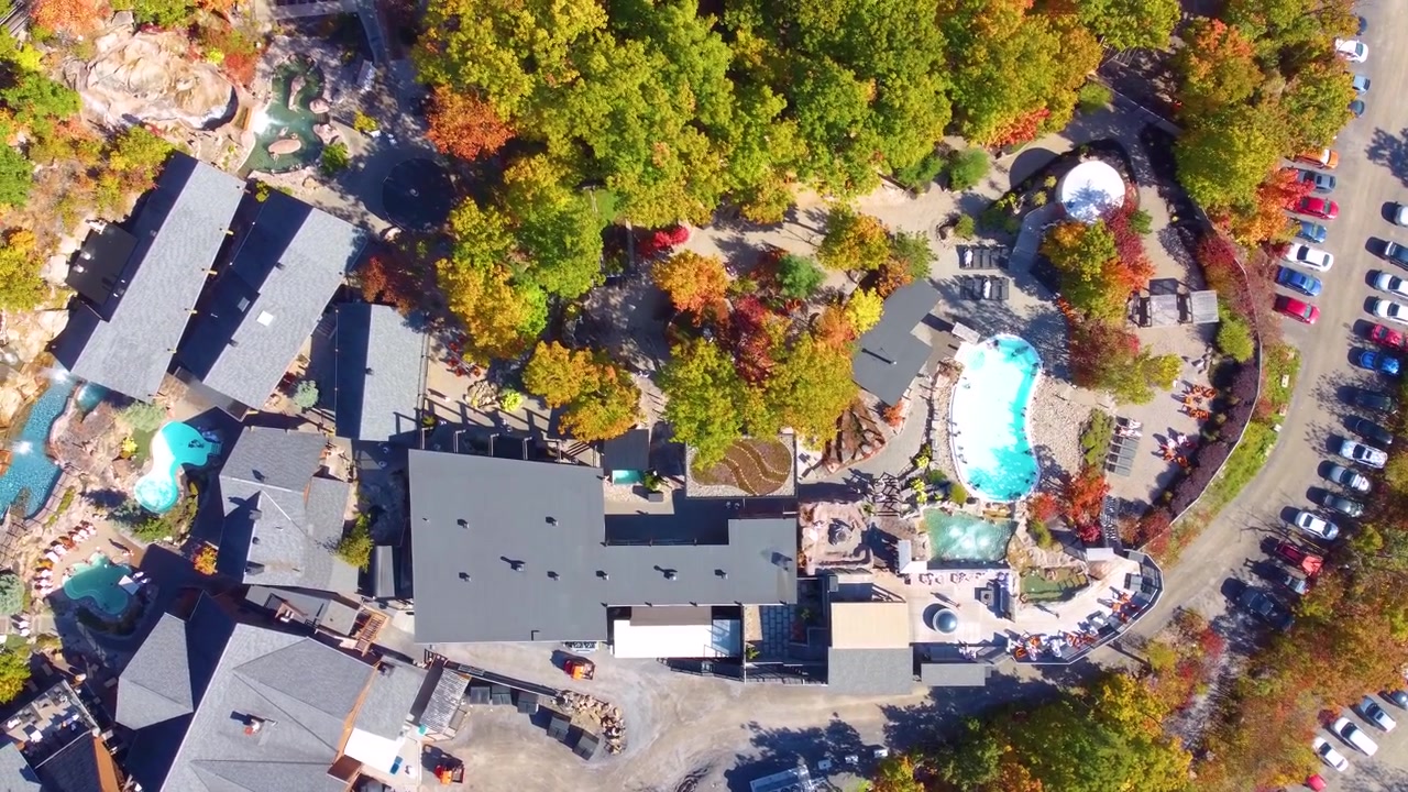 Flying over country club with pools surrounded by trees and greenery. Estrie, Québec, Canada
