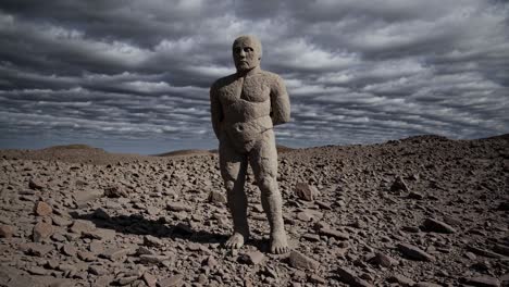 impressive stone guardian statue standing in a desolate rocky landscape under a dramatic cloudy sky, evoking a sense of mystery and ancient history