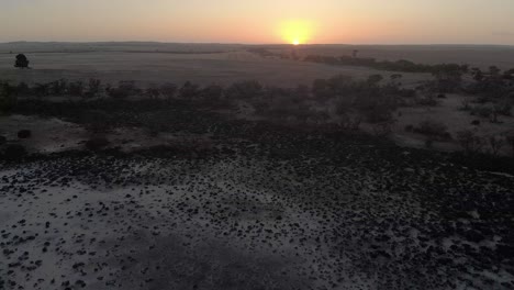 aerial shot orbiting around a sunrise over a salt lake in the australian outback