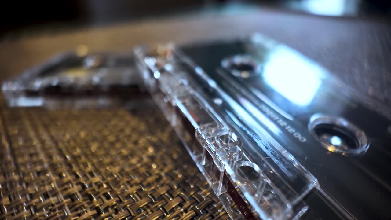 Clear plastic audio cassette tapes sitting on a textured surface, evoking nostalgia for analog sound