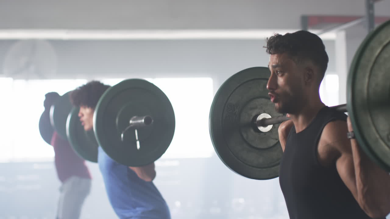 Uomini che sollevano bilancieri e si allenano in palestra, concentrandosi sull'allenamento di forza.