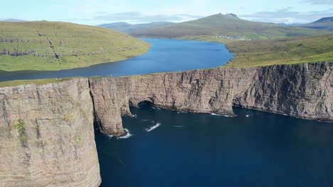 fotografía aérea del meandro del lago sorvagsvatn y el acantilado de traelanipa con excursionistas en su borde