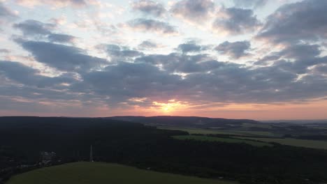 drone view of sunrise with cloudy sky and mountains in the background