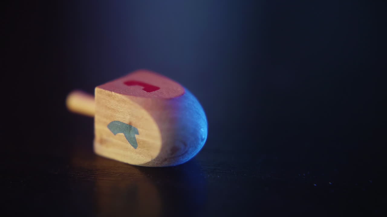 Dreidel di legno che gira e si posa su una superficie scura