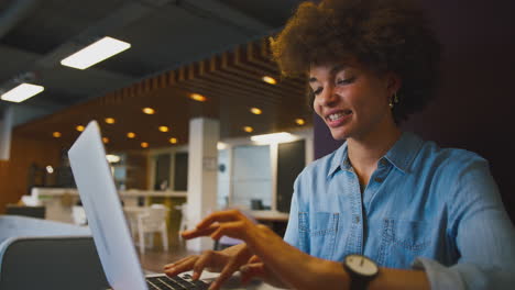 young businesswoman in modern office working on laptop in seating pod