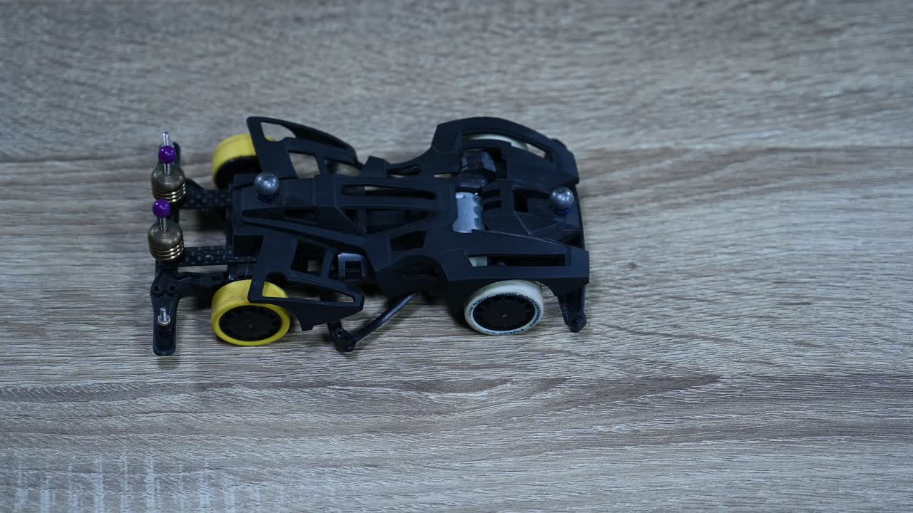 comprobando la alineación y el equilibrio de un mini coche deportivo tamiya dejándolo caer una y otra vez sobre una mesa dentro de una tienda en bangkok, tailandia