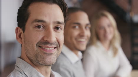 Portrait-of-a-confident-young-business-woman-at-boardroom-table-in-trendy-modern-shared-office-space-a-diverse-team-chatting-together-slow-motion-turning-around-smiling