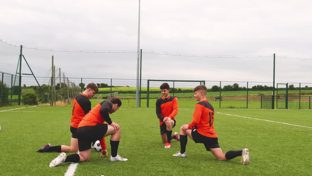 Soccer players kneeling on field, discussing strategy during practice session