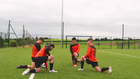 soccer players kneeling on field, discussing strategy during practice session