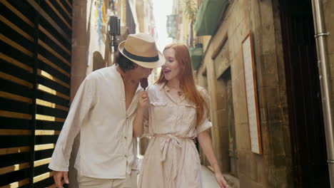 pareja sonriente caminando por la calle de la ciudad vieja juntos. hombre alegre comiendo helado