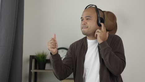 young asian man wearing headphone and listen the music. he stand up and dancing with music.take a rest relax in vacation time.