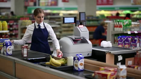 a cashier at a supermarket checkout scans groceries