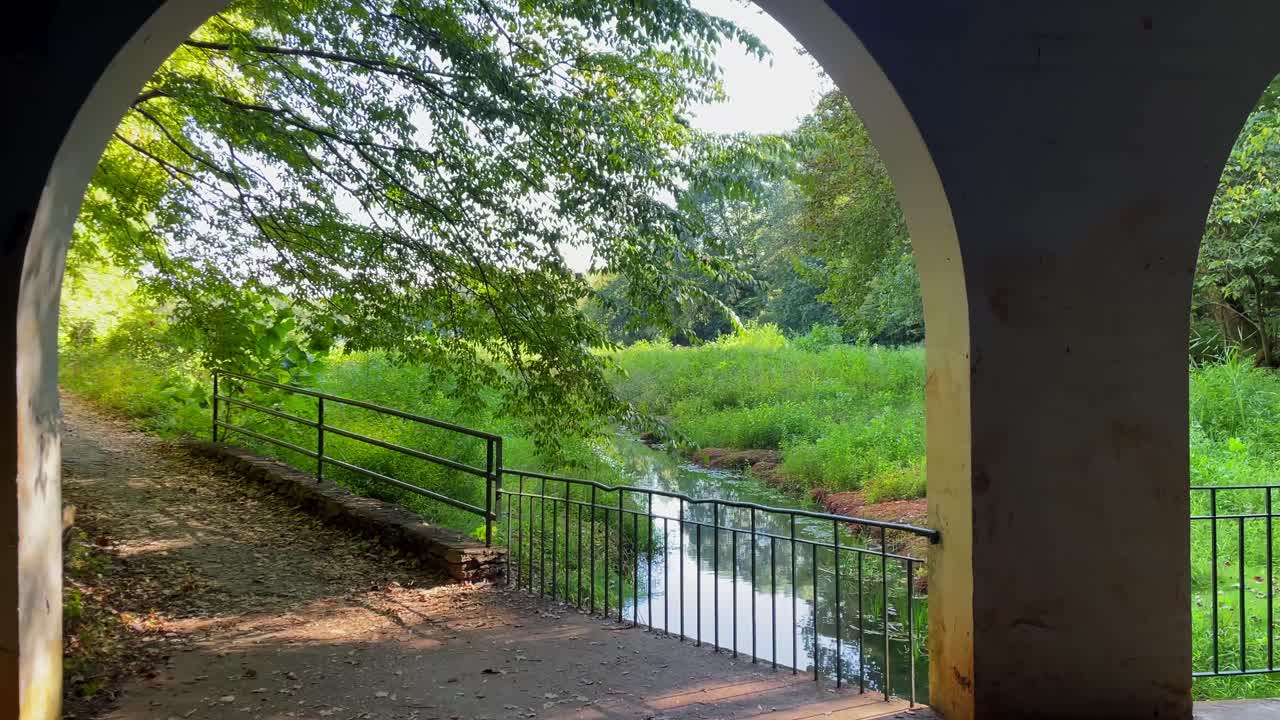 개울과 아름다운 풍경을 드러내기 위해 아치형 통로를 통해 앞으로 이동, 걷기, 돌리 샷