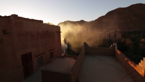 todra gorge moroccan style kasbah housing in desert with fast moving rooftop smoke rising into sunse