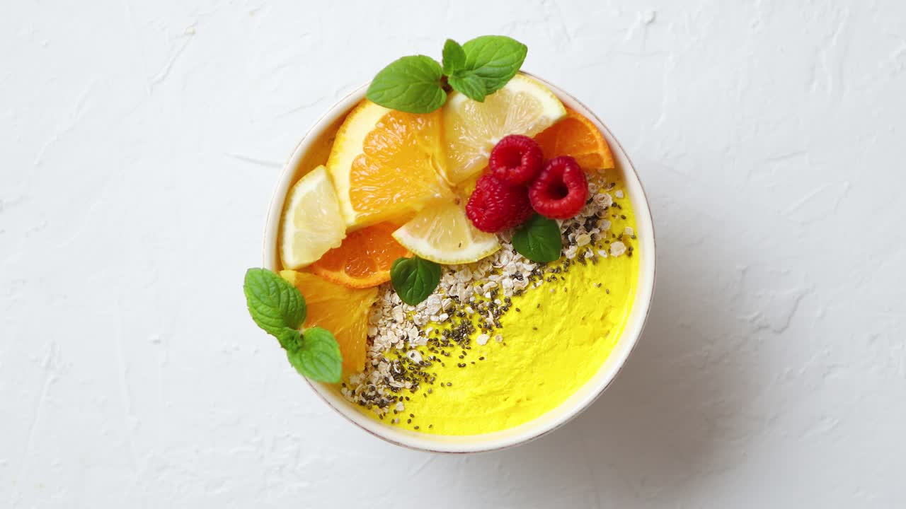 Smoothie jeruk segar lezat atau yogurt disajikan dalam mangkuk dengan raspberry, irisan jeruk, dan biji chia.