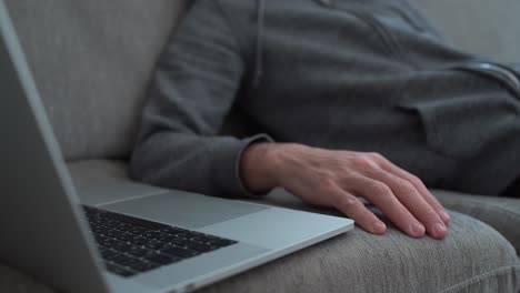 Müder-Kerl,-Der-Langsam-Auf-Seinem-Computer-Tippt,-Während-Er-Auf-Der-Couch-Sitzt