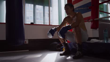 hombre caucásico descansando en el ring de boxeo