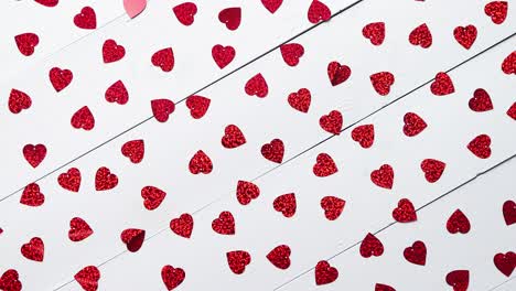 Vlentine's-Day-composition--Heart-shaped-sequins-placed-on-white-wooden-table