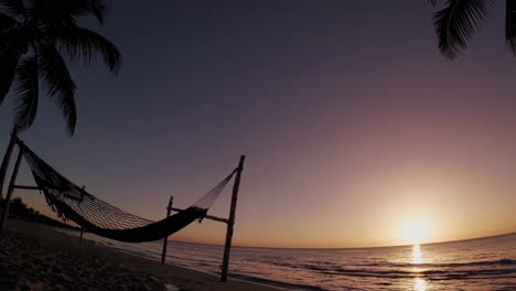 a serene beach sunset with a hammock, captured in a wide-angle shot