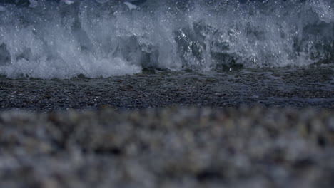 small waves breaking on the shore of pebble beach in marbella spain, 4k, slow motion