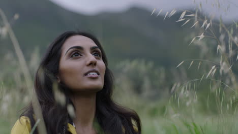 beautiful young indian woman hiker looking up enjoying peaceful travel adventure in calm countryside background smiling happy independent