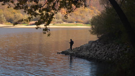 man fishing in a lake during autumn