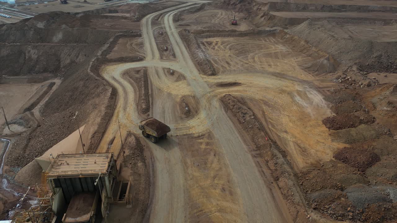 Hauler Dump Truck driving at nickel mine site in Western Australia, aerial tracking shot