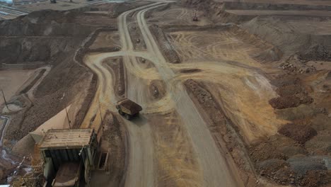 Hauler-Dump-Truck-driving-at-nickel-mine-site-in-Western-Australia,-aerial-tracking-shot