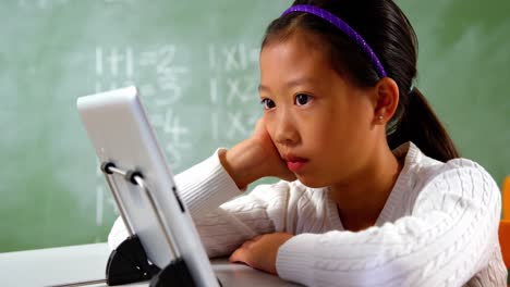 schoolgirl using digital tablet in classroom at school