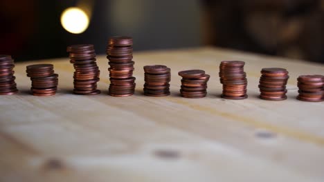 many small cent coins stacks lined up in a row on a wooden board rotate against a dark background