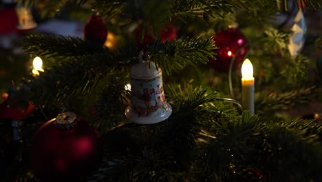 primer plano de una campana en un árbol de navidad con luces navideñas.