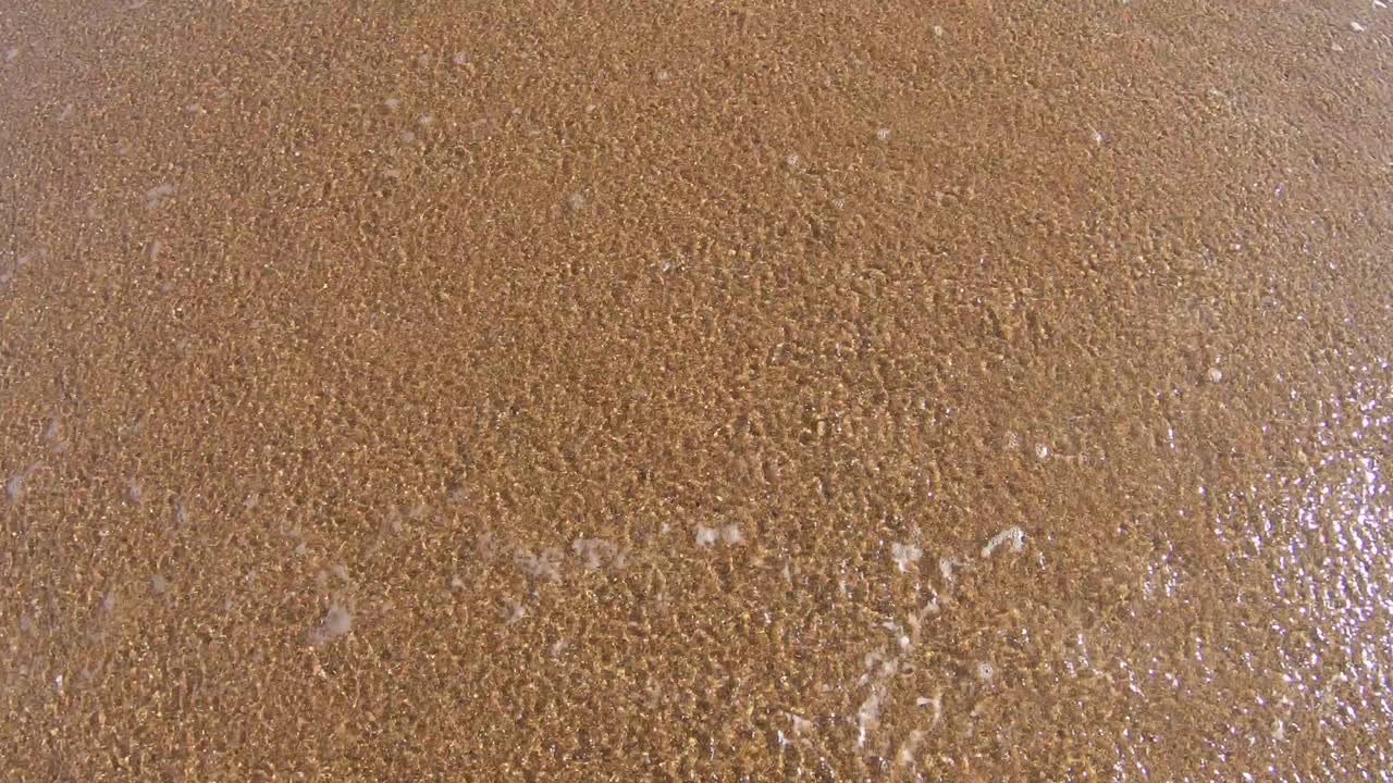 모래를 가로질러 움직이는 파도의 하향식 샷