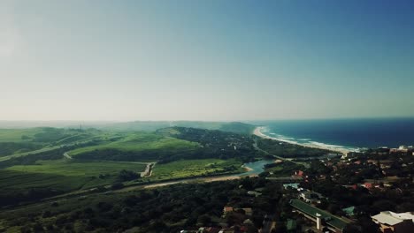 Luftaufnahmen,-Die-Von-Einer-Drohne-Von-Scottburgh-Beach-Und-Landgrasfeldern-Mit-Wohnhäusern-Mit-Blick-Auf-Das-Meer-In-Kwa-Zulu,-Natal,-Südafrika,-Gefilmt-Wurden