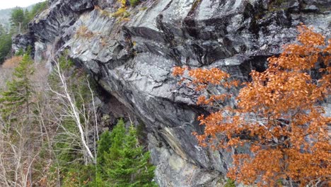 Overhanging-Rocky-Cliff-on-Hillside-with-Pine-Tree-Forest-in-the-Background-with-Light-Snow-in-Mount-Washington-State-Park,-New-Hampshire,-USA