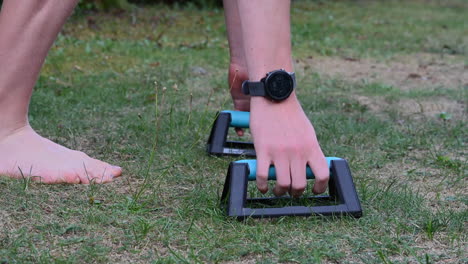 un joven atleta de calistenia está preparando sus manos en parallettes, pequeñas barras para hacer flexiones para hacer crecer su pecho